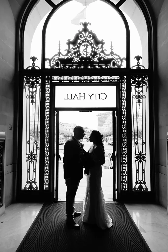 Black and white silhouette of bride and groom at front door of San Francisco City Hall