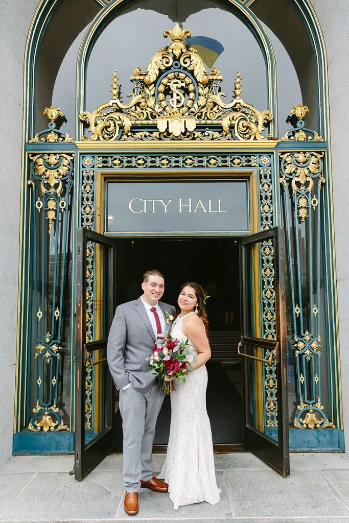 Bride and groom stand together at front doors