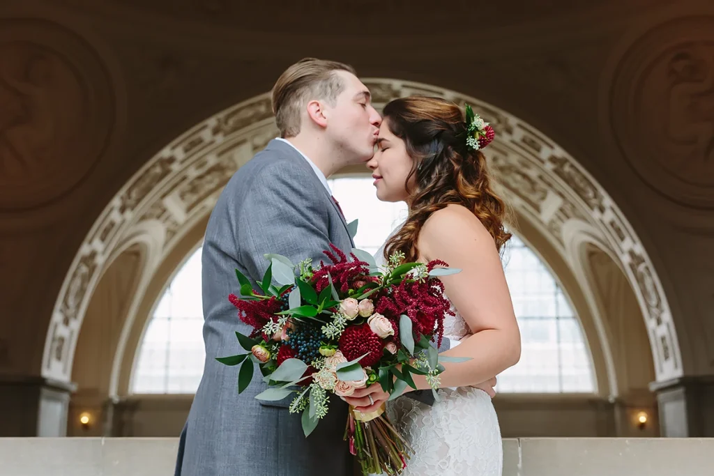 Groom kisses bride on forehead