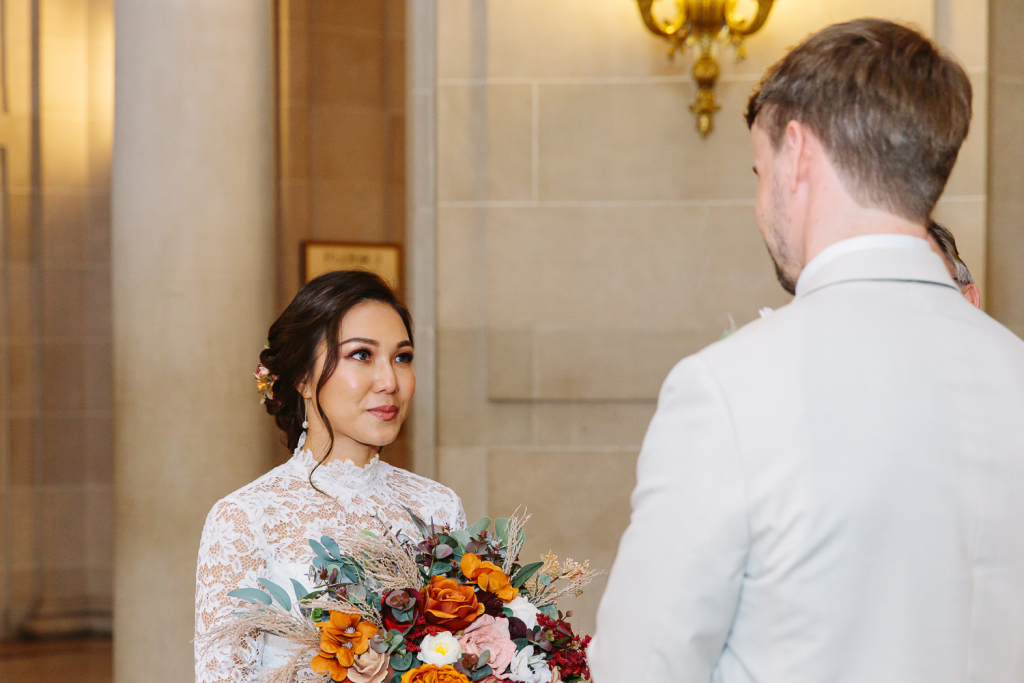 Bride smiles at groom during wedding ceremony