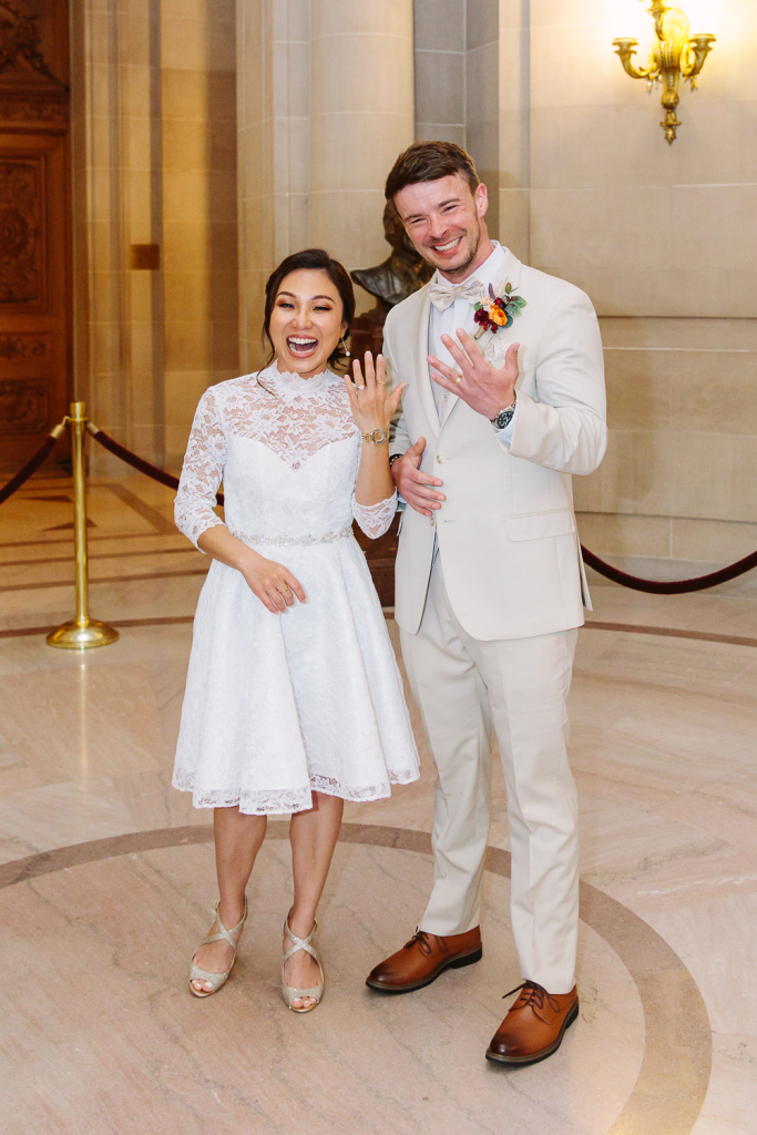 Couple smile and show off their wedding rings