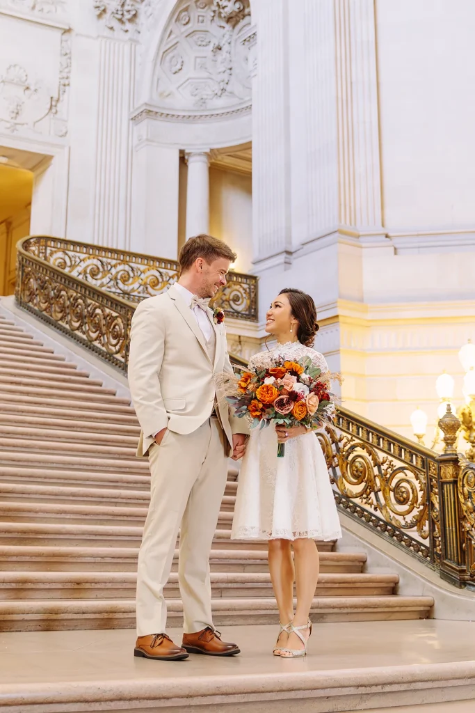 Bride and groom stand together on the Grand Staircase at a City Hall SF wedding