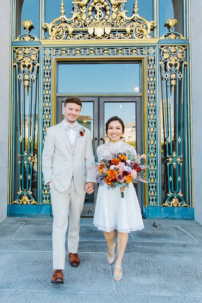 Couple hold hands and walk together at their City Hall SF elopement