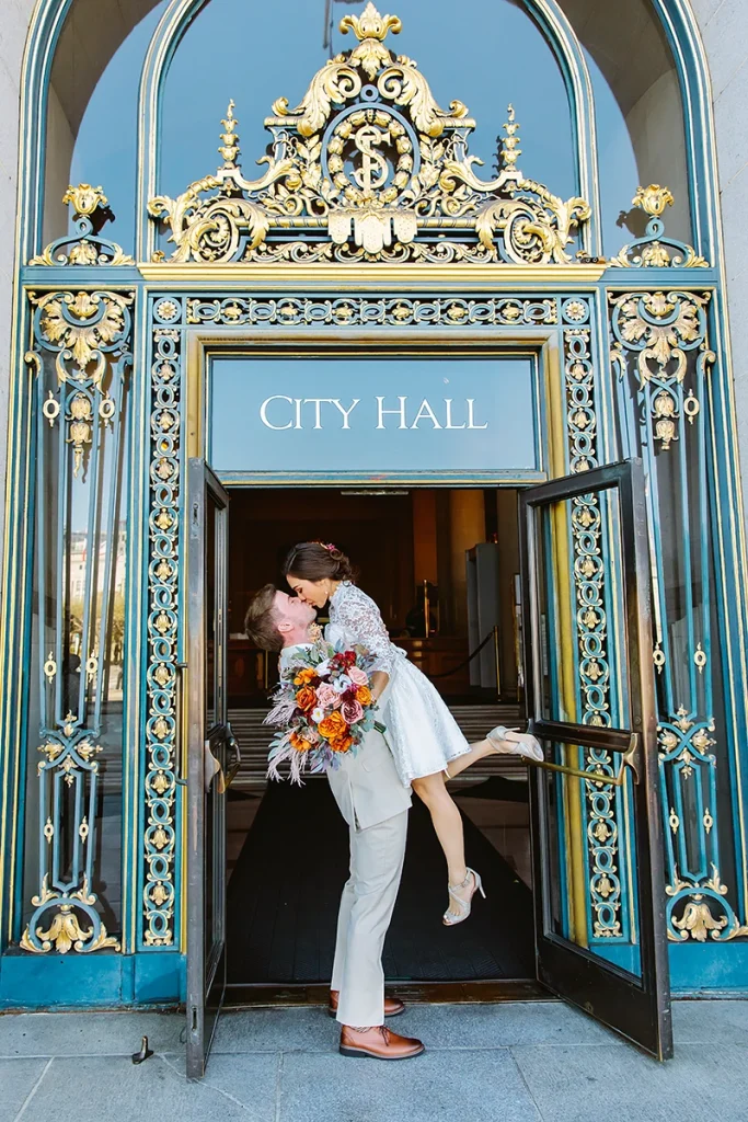 Groom picks up bride at front door of City Hall SF elopement