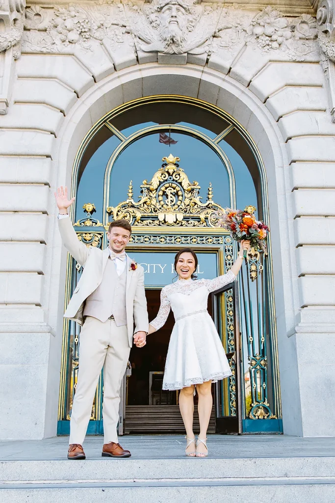 Couple raise hands in triumph at their City Hall SF wedding