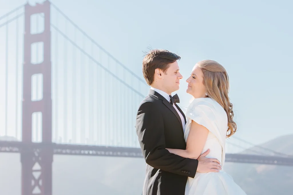 Bride and groom hug with the Golden Gate Bridge of San Francisco in the background