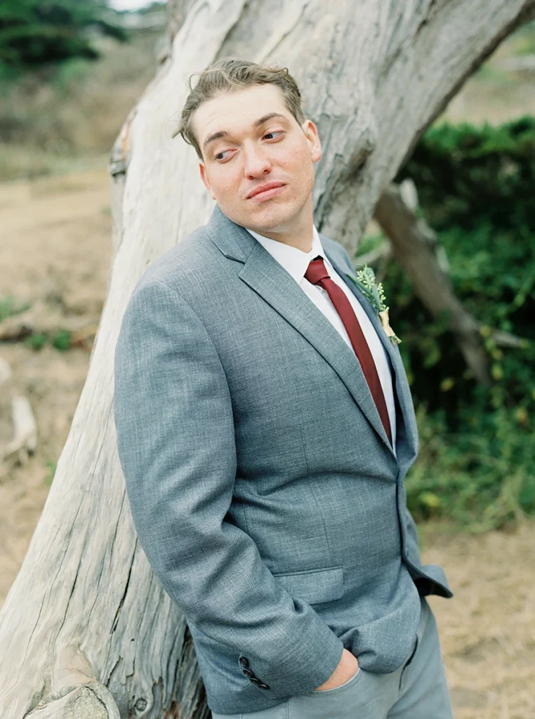 Groom leaning on a tree