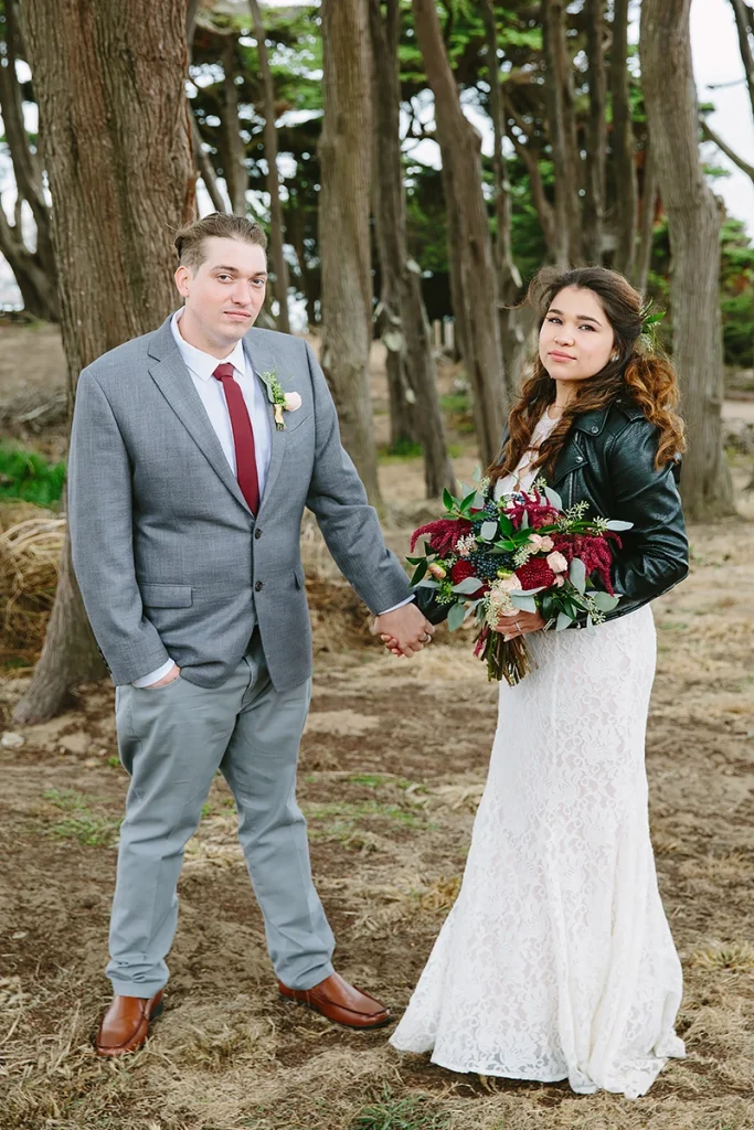 Bride and groom stand apart and hold hands
