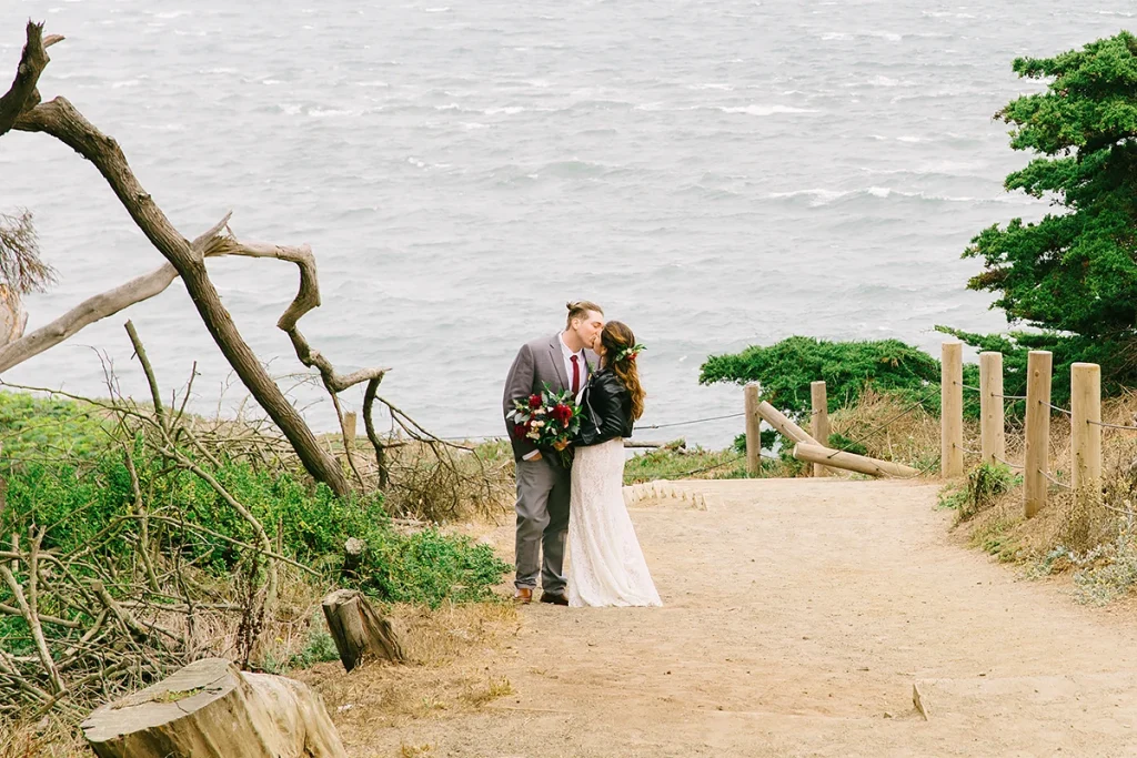Bride and groom share a kiss with the Pacific Ocean in the background