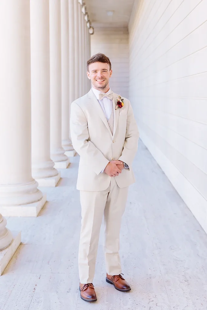 Full length portrait of groom wearing a light tan suit with brown shoes