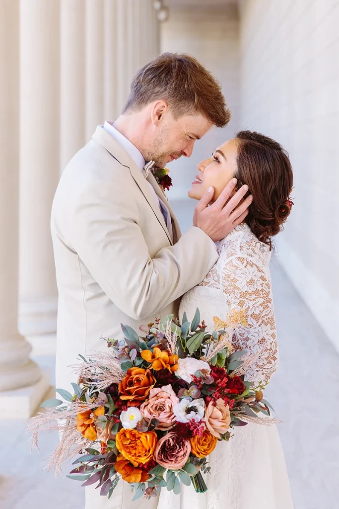 Groom embraces bride and touches her cheek