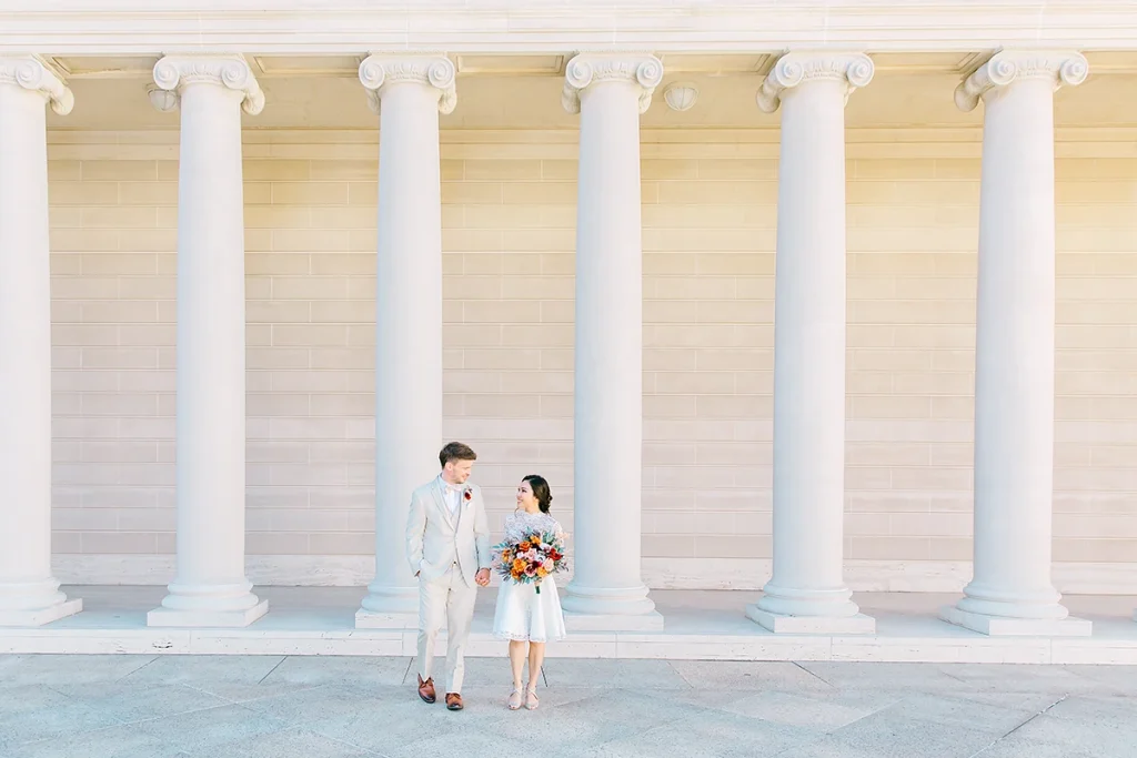 Couple walking together with the grand columns of the Legion of Honor museum behind them