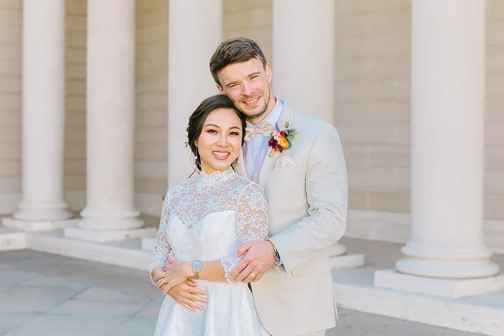Groom stands behind bride and holds her closely at their Legion of Honor wedding in San Francisco