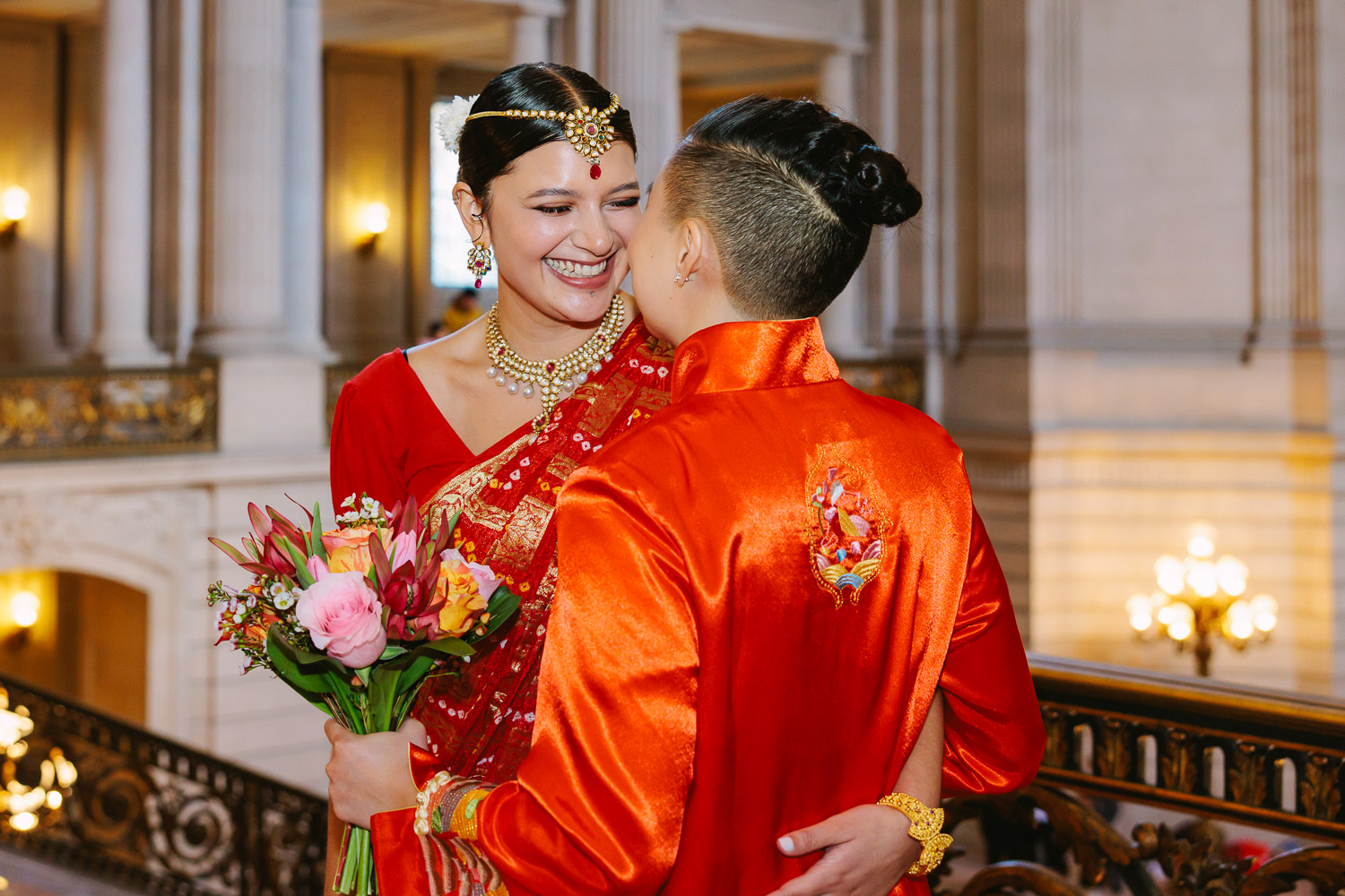 Couple dressed in red laugh and smile before their wedding ceremony