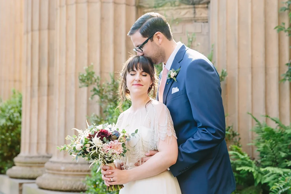 Groom kisses bride on top of her head