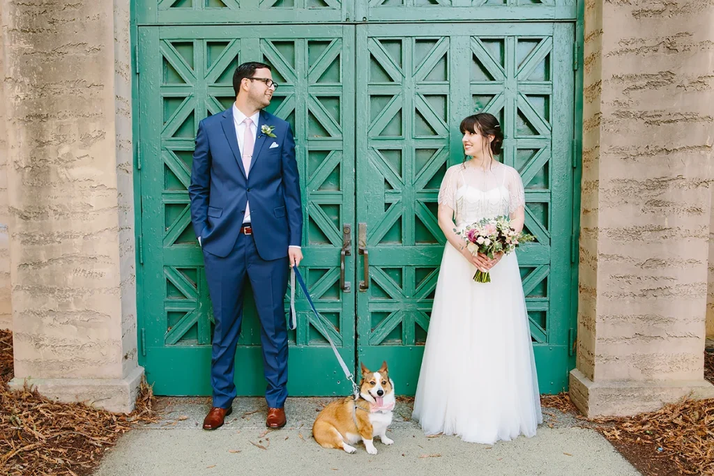 Bride and groom smile at each other with large green doors in the background