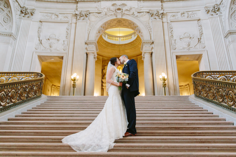 Bride and groom kiss on the stairs at SF City Hall