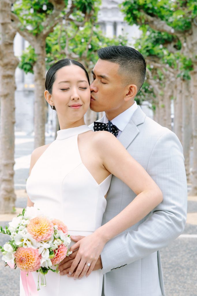 Groom holding his bride and giving her a kiss on her cheek
