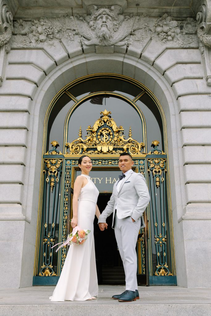 Bride and groom standing in front of the front door at Wedding Ceremony on the Fourth Floor at San Francisco City Hall