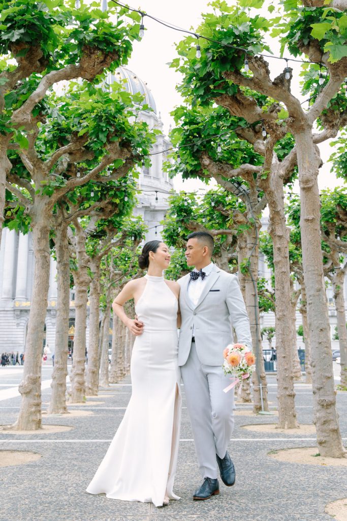 Bride and groom walking amongst the sycamore trees in Civic Center Plaza in San Francisco