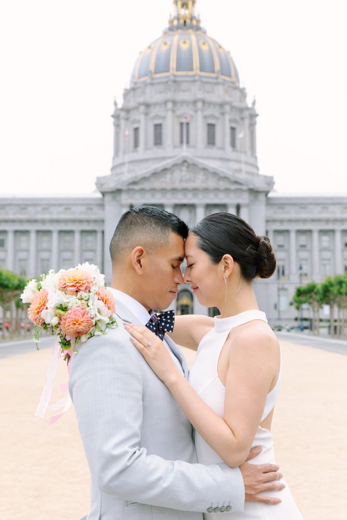 Bride and groom holding each other. Standing in front of Wedding Ceremony on the Fourth Floor at San Francisco City Hall