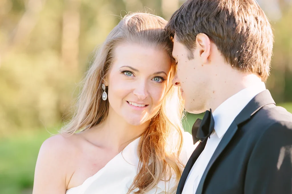 Closeup of bride smiling while groom leans on her