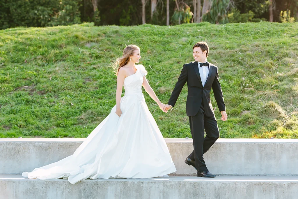 Bride and groom in grand wedding dress and black tuxedo walk together