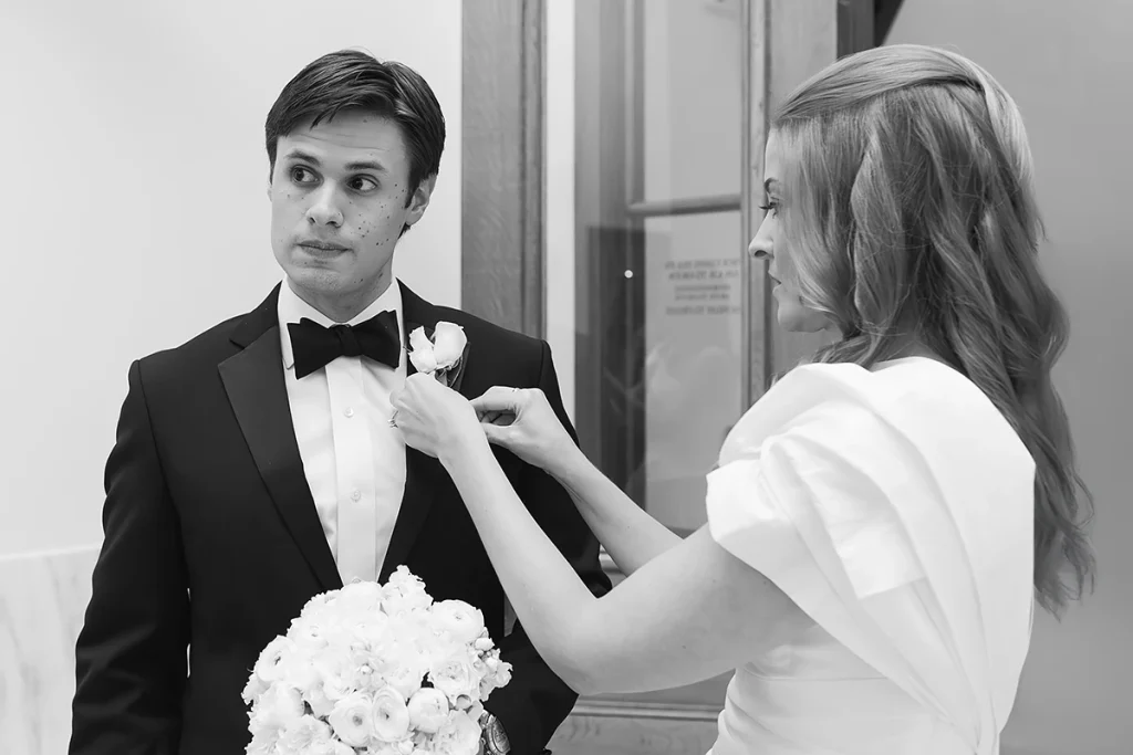 Bride helps groom with his bouttonaire
