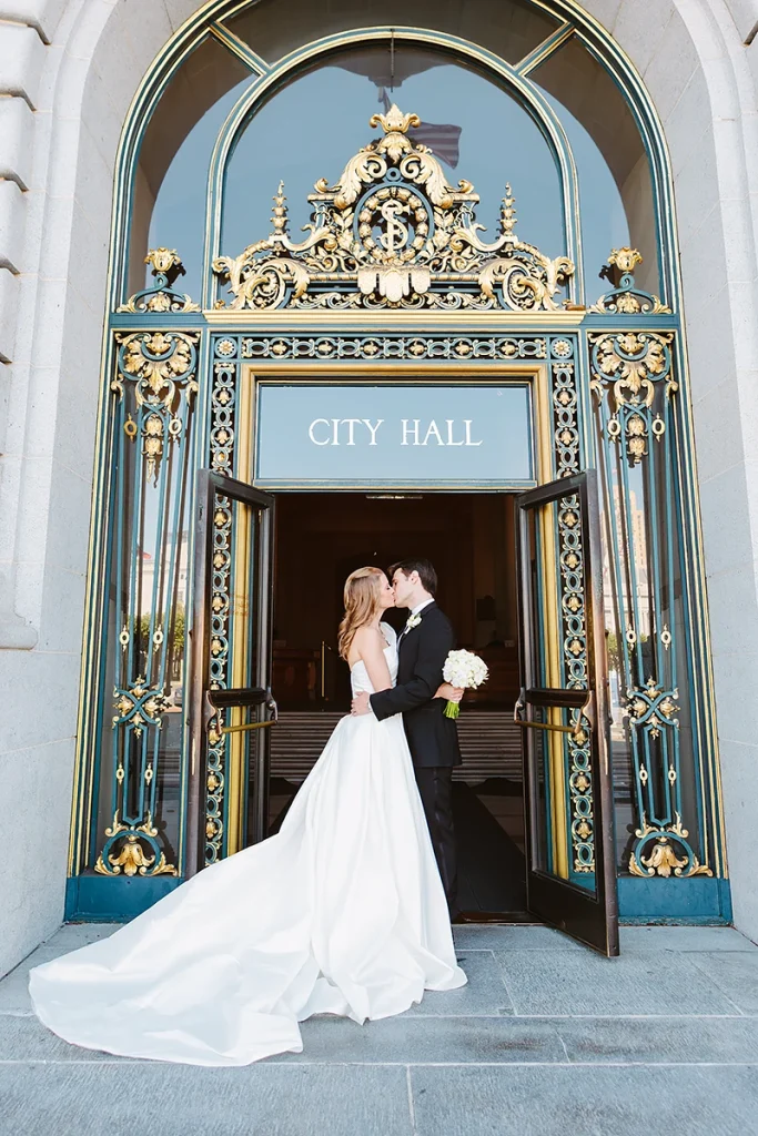 Bride and groom kiss at the front door of San Francisco City Hall