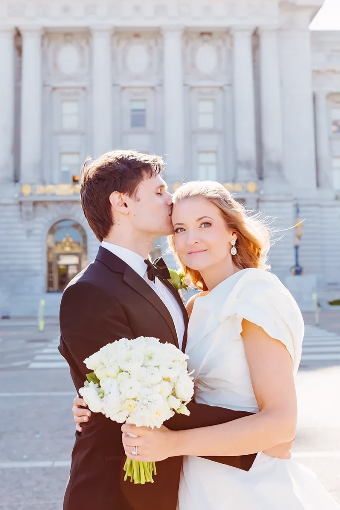 Groom kisses bride on her head