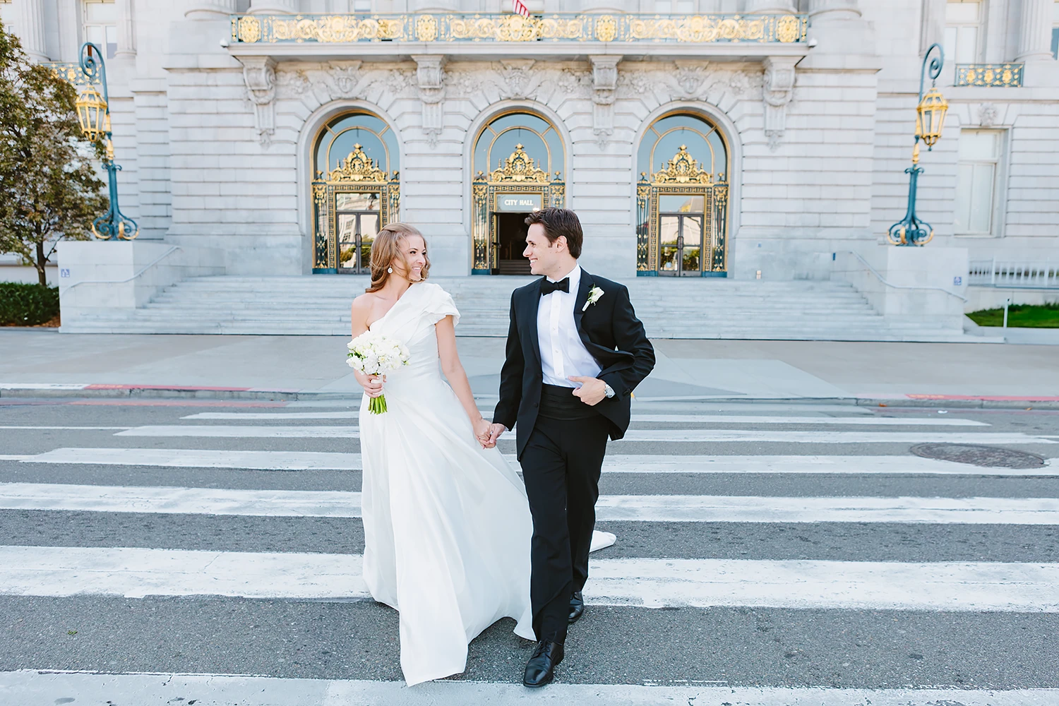 Bride and groom smile and cross the street together after their SF City Hall elopement wedding