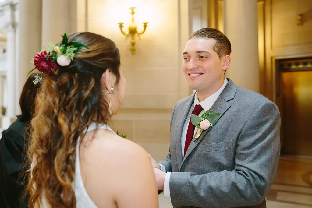 Groom smiles at bride during vows