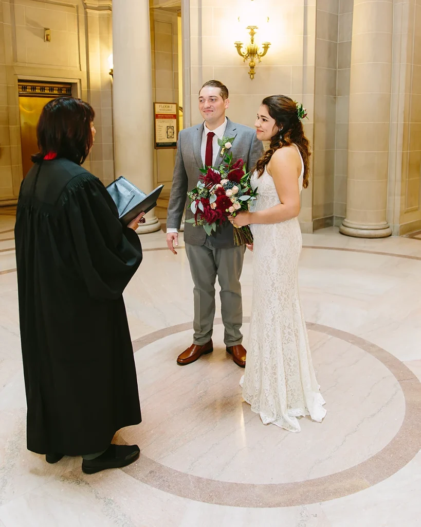 Bride and groom listen to officiant during SF City Hall public civil ceremony