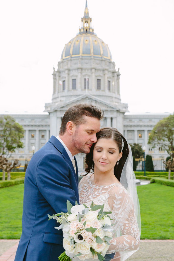 San Francisco City Hall wedding photographer. Bride and groom hold each other closely with City Hall in the background