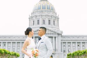 Bride and groom standing in Civic Center Plaza with a view of SF City Hall in the background