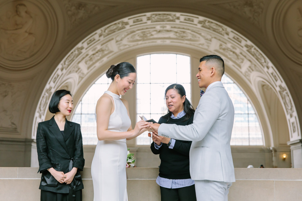 Bride places ring on the hand of the groom