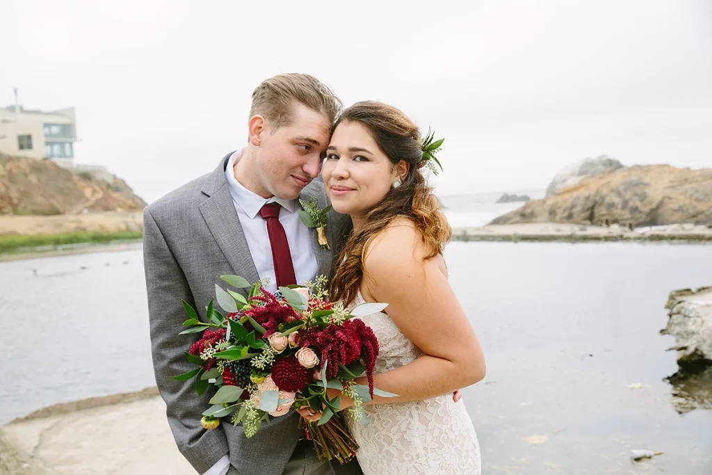 Groom leans on bride as she smiles