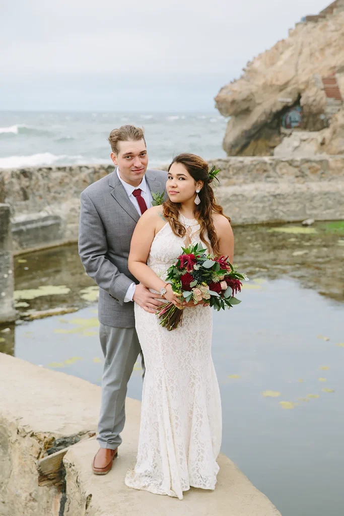 Bride and groom with ocean behind them